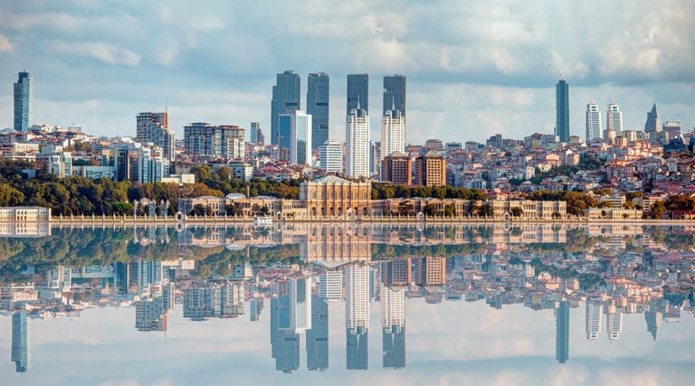 Dolmabahce palace against coastal cityscape with modern buildings under cloudy sky istanbul city