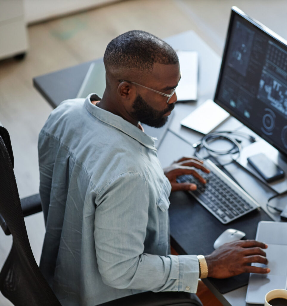Professional sitting at desk typing and reading from notepad